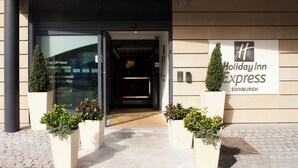 The entrance to a Holiday Inn Express in Edinburgh, featuring a modern design with a glass facade, a signboard, and potted plants. - Holiday Inn Express Edinburgh Royal Mile by IHG (Edinburgh)