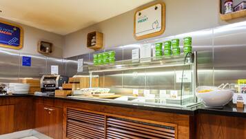 A buffet area with various food options, including a section for fresh juices and a display of cereal boxes.