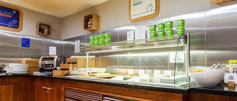 A buffet area with various food options, including a section for fresh juices and a display of cereal boxes.