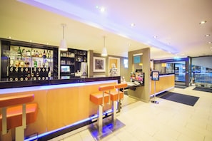 A bar area with a counter, bar stools, and a variety of liquor bottles. - Holiday Inn Express Edinburgh Royal Mile by IHG (Edinburgh)