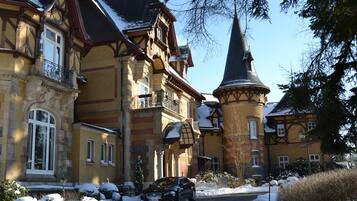 Un edificio grande e histórico con una torre y varias ventanas, rodeado de nieve.