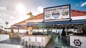 Un restaurante con fachada de azulejos, mesas al aire libre y un letrero con ilustraciones náuticas.