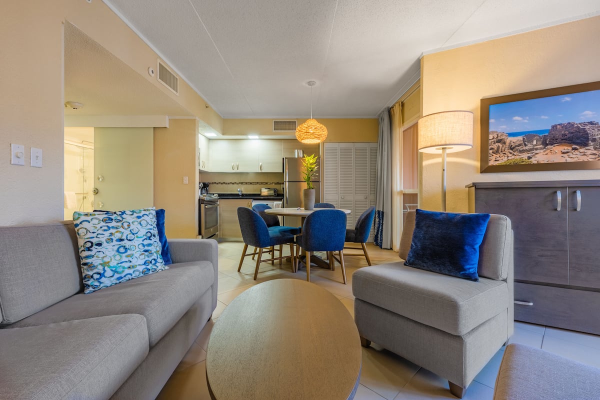 A modern living room with a grey sofa, blue chairs, and a round coffee table.