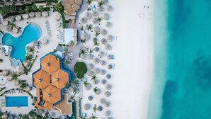 Vista aérea de un resort con piscina, sombrillas de playa y zona de playa.