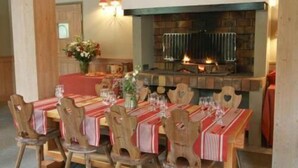 Zona pranzo con camino, sedie in legno e tavolo apparecchiato per un pasto.