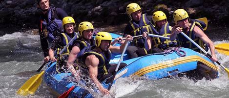 Un grupo de personas en una balsa inflable azul navega por un río.