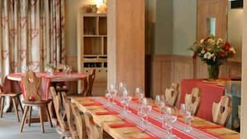Un comedor con mesas y sillas de madera, manteles rojos y copas de vino preparadas para una comida.