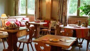 Un comedor acogedor con muebles de madera, una mesa dispuesta con platos y vasos, y una ventana con cortinas.
