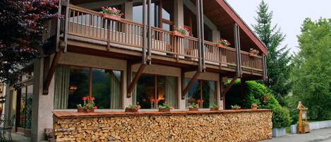A two-story building with a balcony, stone wall, and wooden deck.
