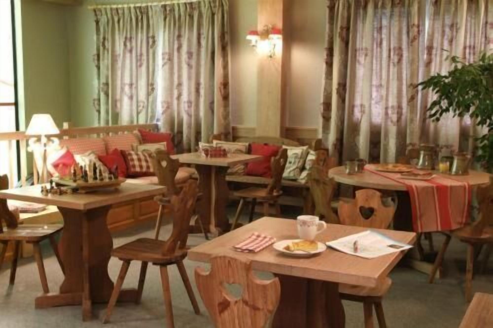 Un comedor con muebles de madera, incluyendo mesas y sillas, y una planta en la esquina.