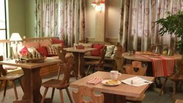 Un comedor con muebles de madera, incluyendo mesas y sillas, y una planta en la esquina.