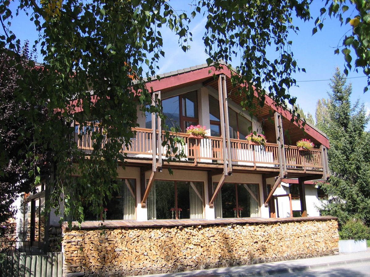 A two-story building with a balcony, stone foundation, and wooden railings.