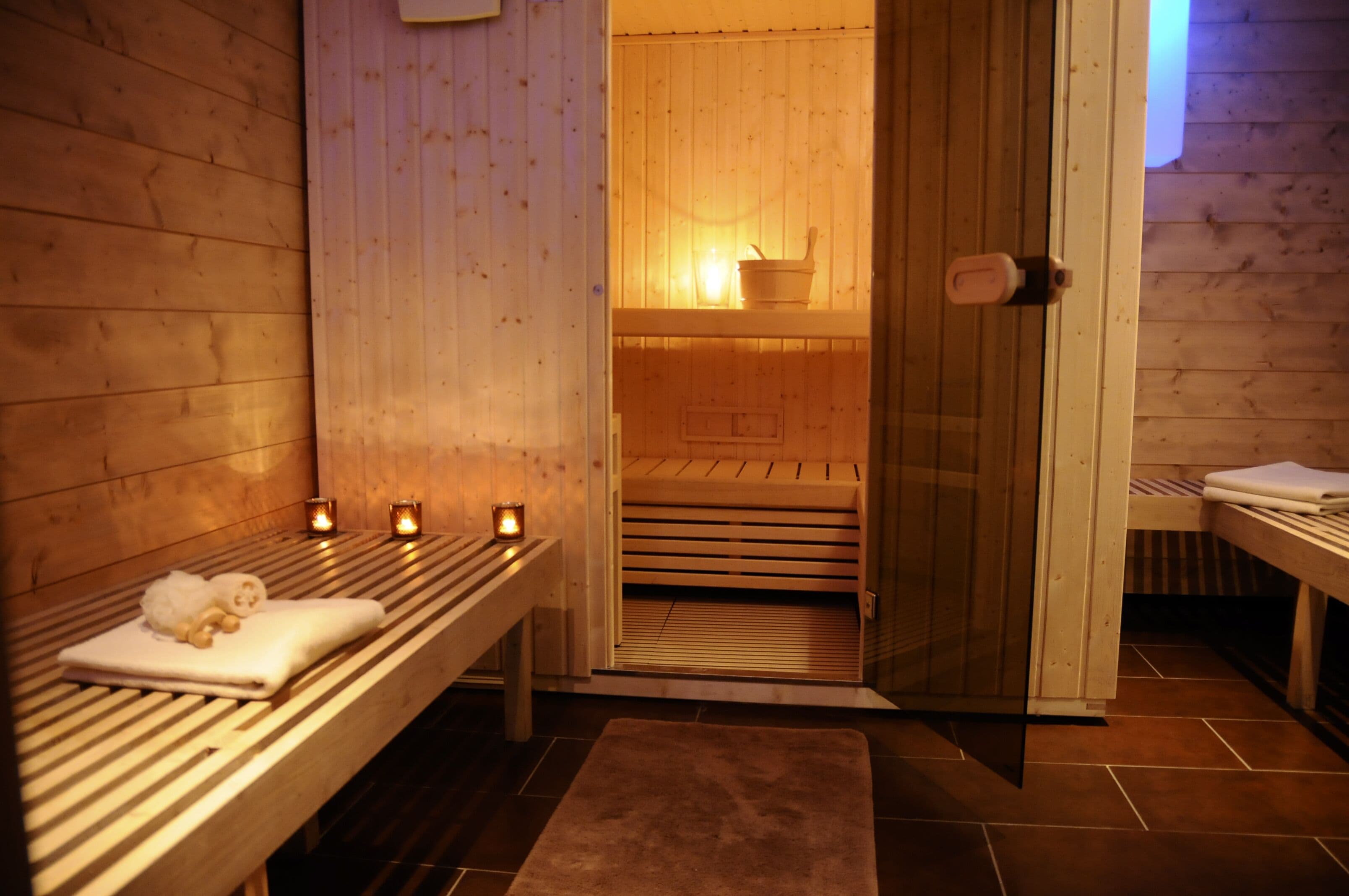 Una sauna de madera con bancos, velas y un banco con toallas.