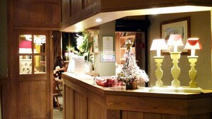 Un mostrador de recepción de madera con un pequeño árbol de Navidad y lámparas.