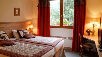 A hotel room with two beds, a desk with a chair, a television, and a window with curtains.