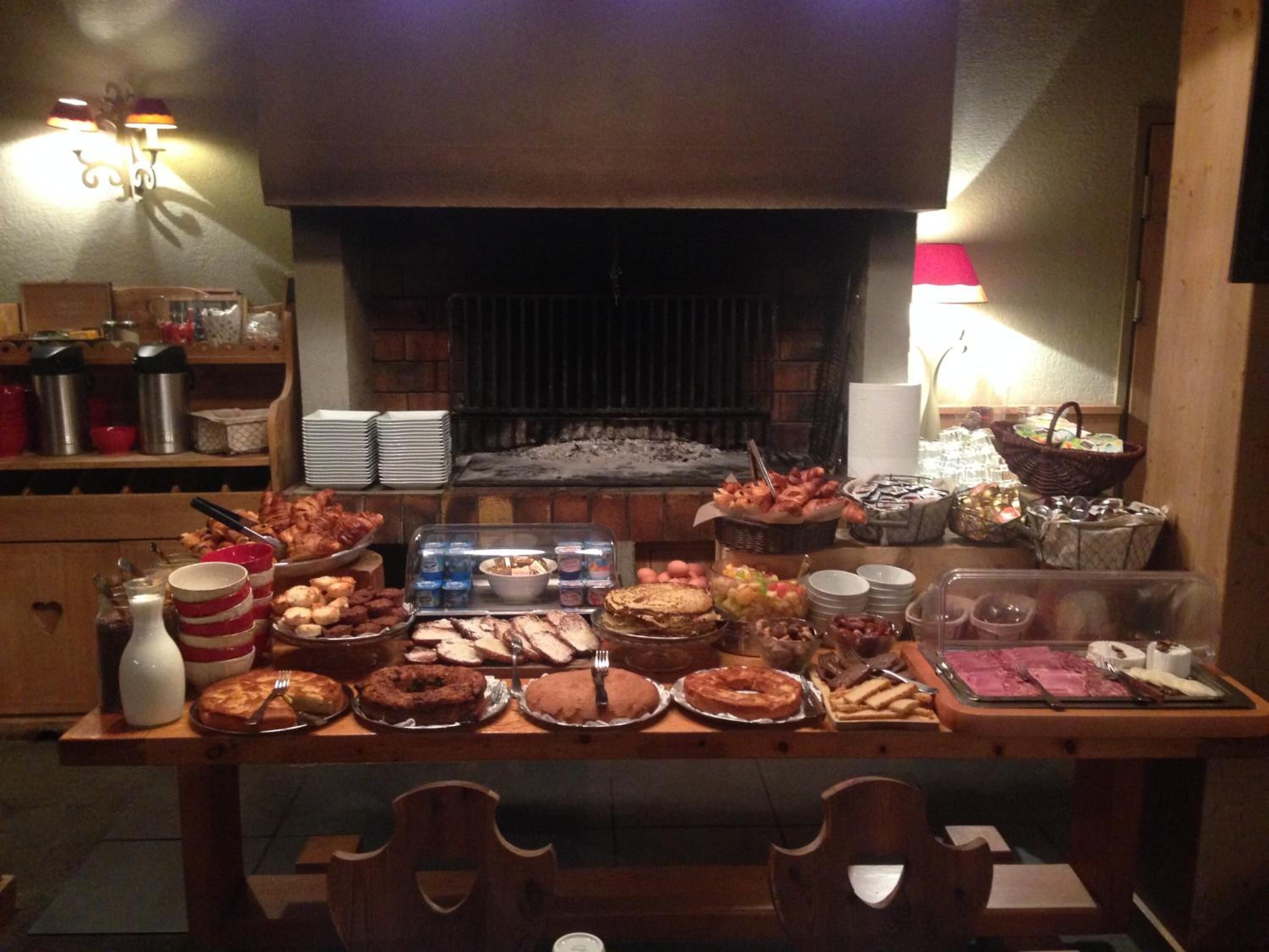 A buffet table with various food items and a brick fireplace in the background.