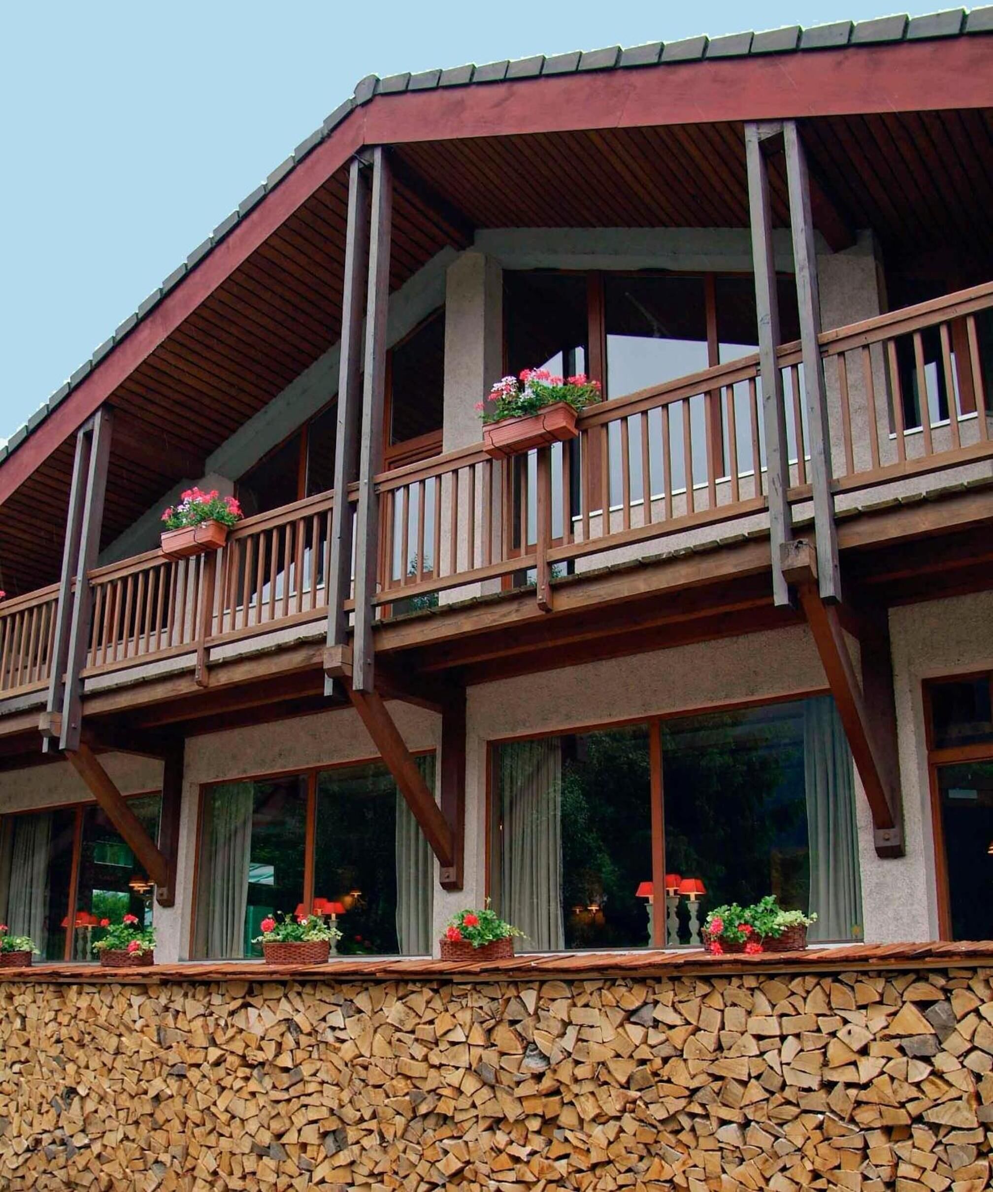 A multi-story building with a stone foundation, wooden balconies with railings, and windows with curtains.