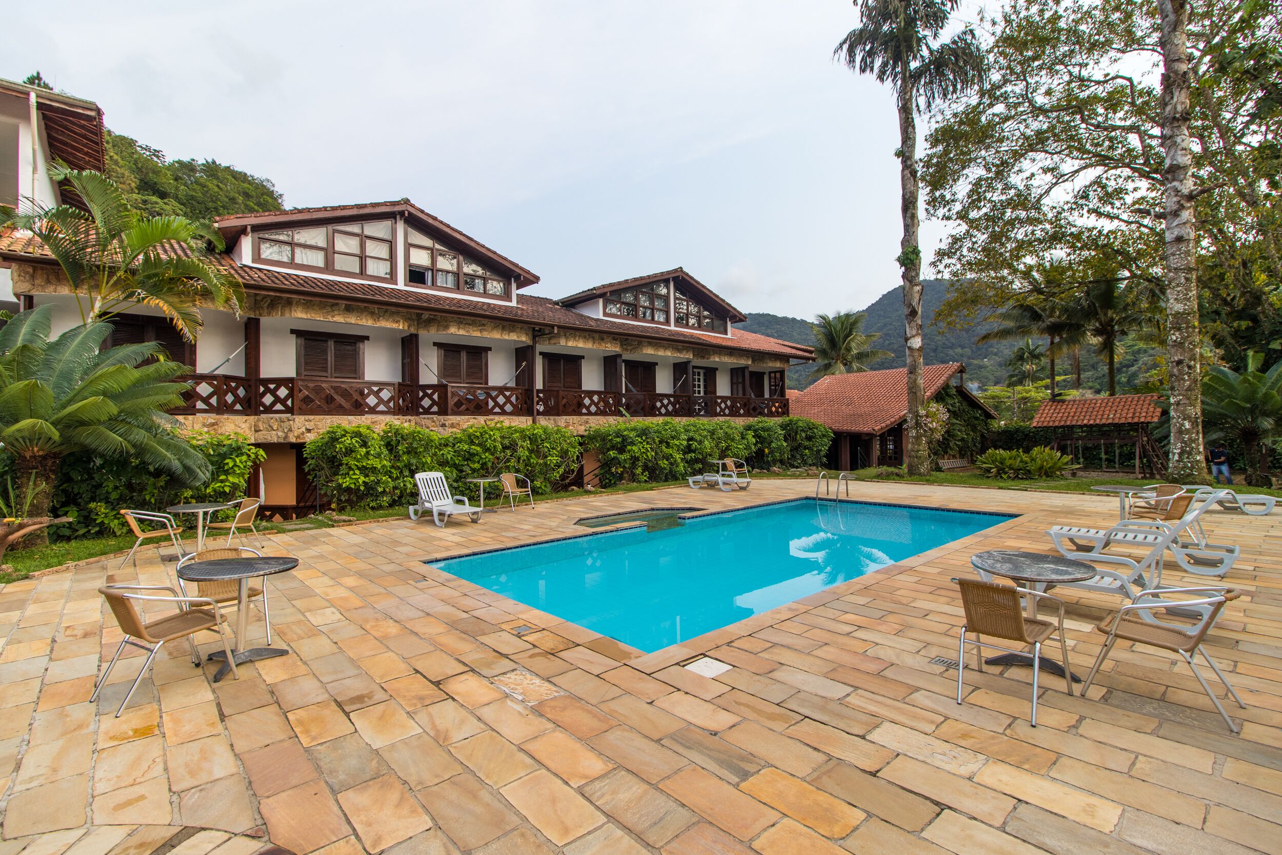 A pool area with lounge chairs and a building with a balcony.