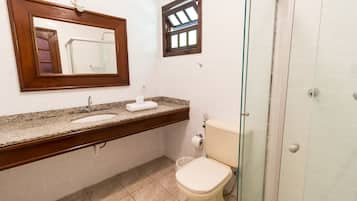 Un baño con lavamanos, espejo, inodoro y ducha.