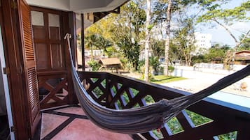 Una hamaca en un balcón con vistas a una piscina y follaje circundante.