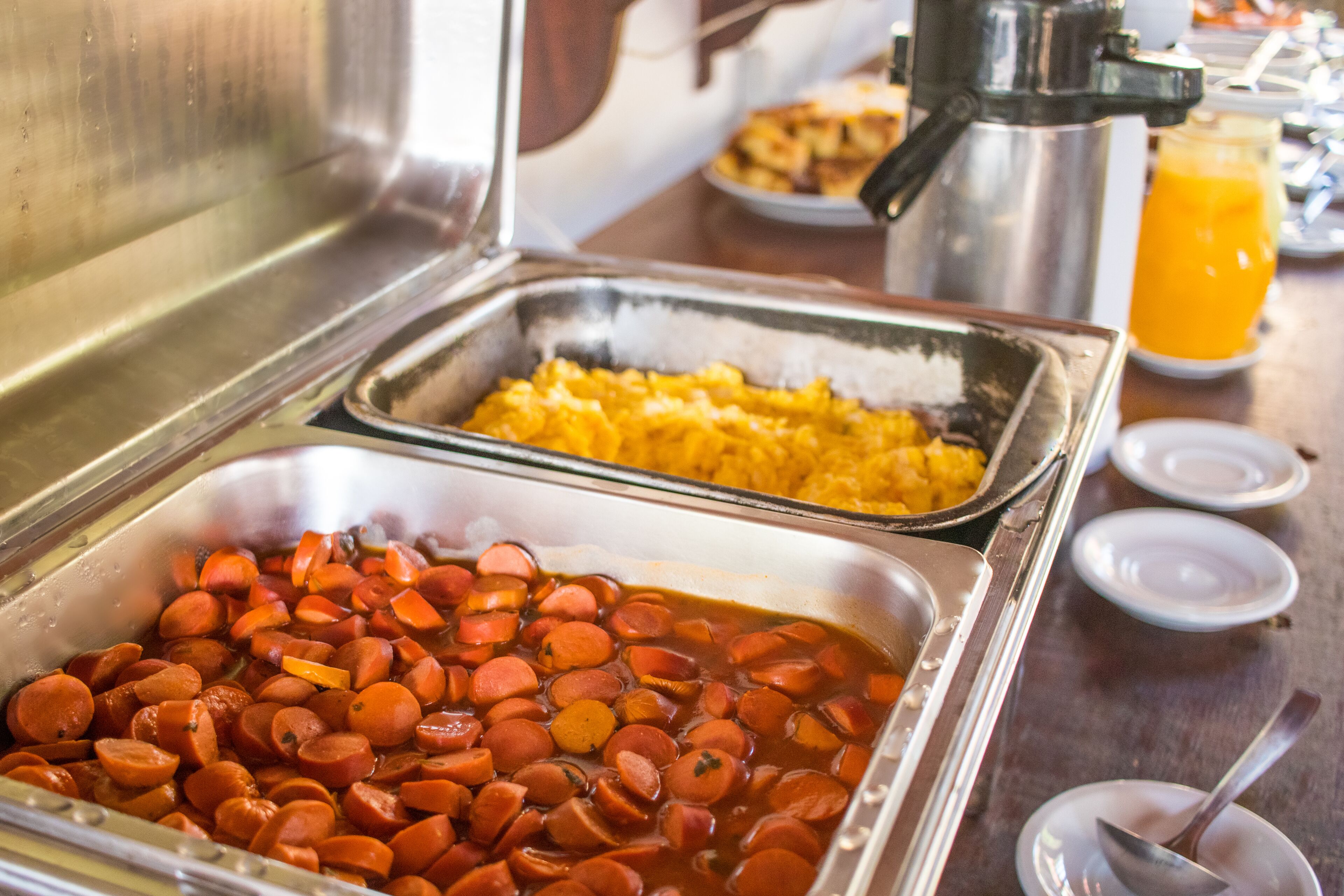 A buffet with various food items including sausages and rice.