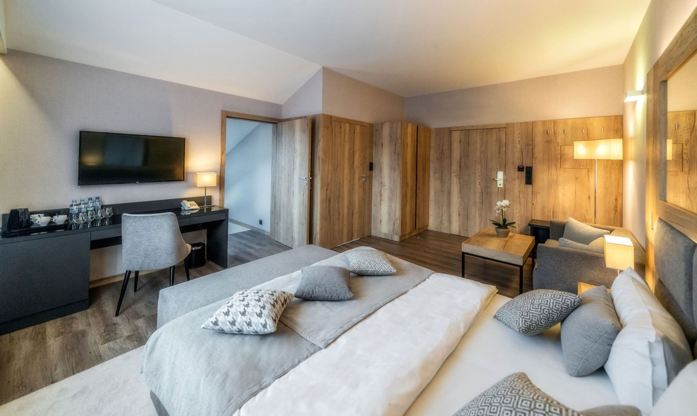 Una habitación de hotel con cama, escritorio, silla, televisión y armario.