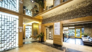 A spacious lobby with a stone wall, a glass display of wine bottles, and a seating area with a view of the outdoors. - Hotel Meta Resort & Vine SPA (Szczyrk)
