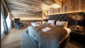 A modern bedroom with a wooden ceiling, a large bed with a tufted headboard, a bedside table with a lamp, and a chair. - Hotel Meta Resort & Vine SPA (Szczyrk)