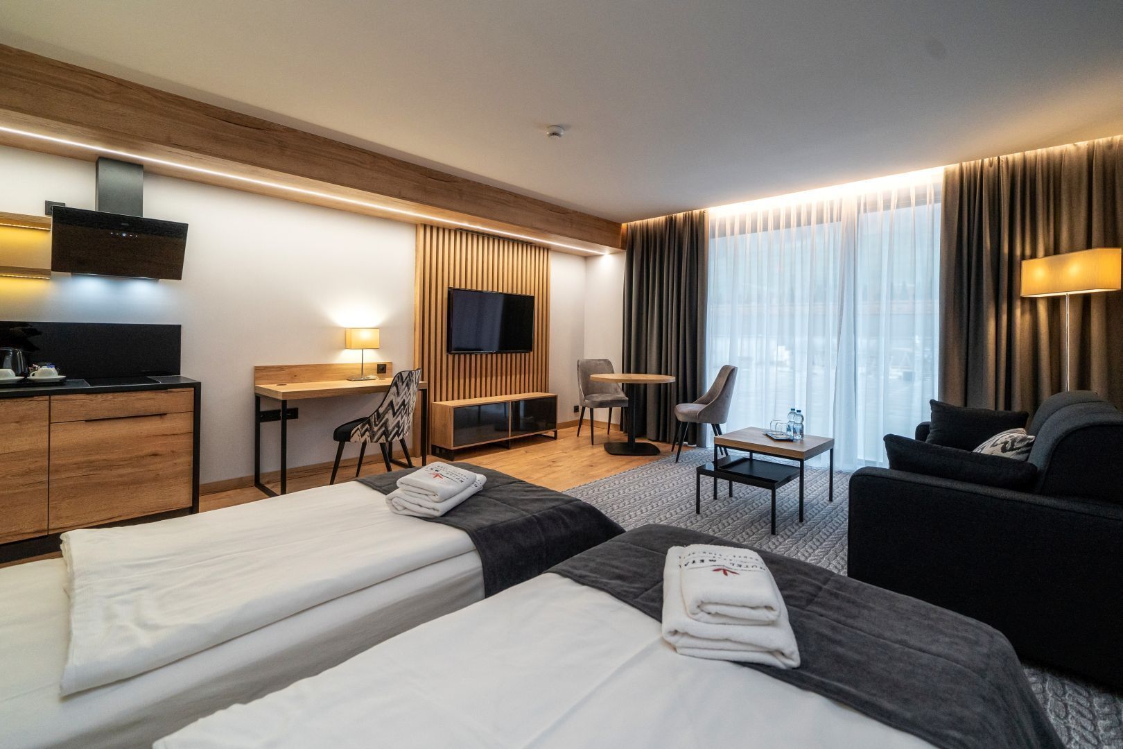Une chambre d’hôtel avec deux lits, un bureau, une télévision, un canapé et une chaise.