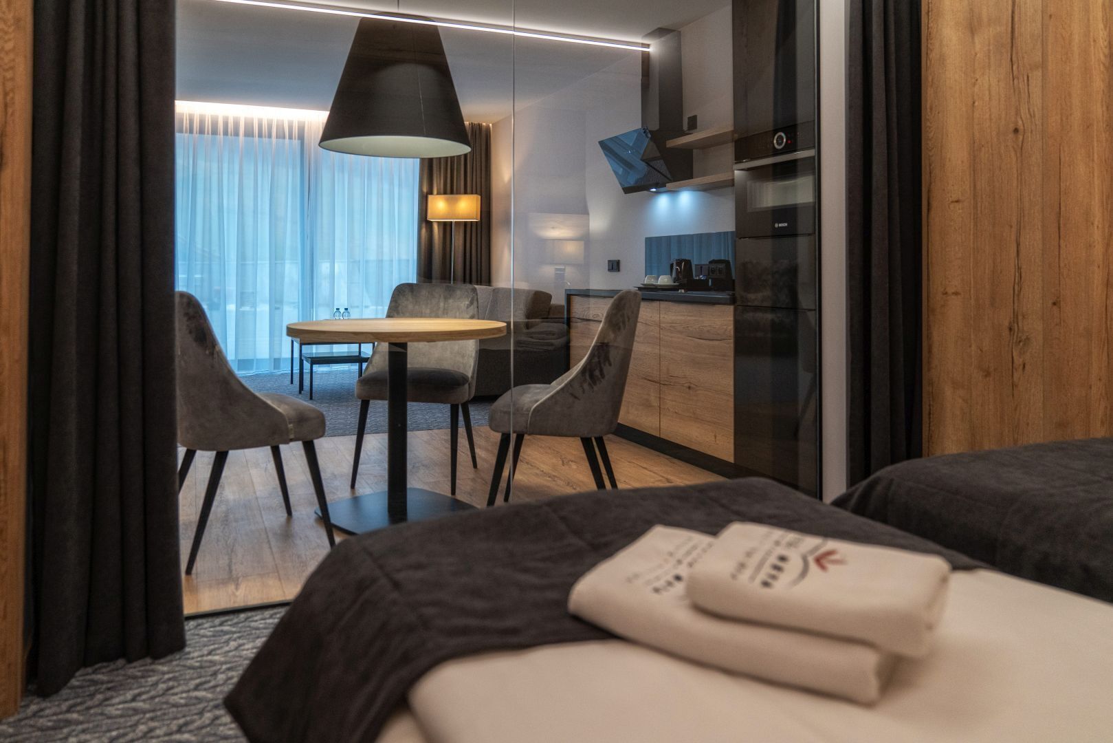 A modern hotel room with a bed, a desk, and a dining area.