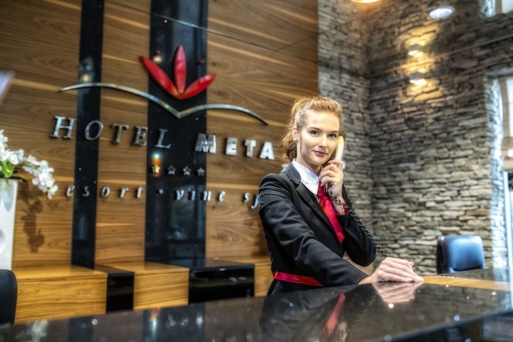 Un mostrador de recepción de hotel con un panel de pared de madera y una pared de acento de piedra.
