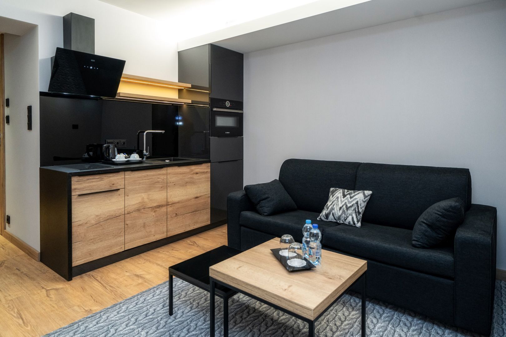 A compact living space with a kitchenette, a sofa, and a coffee table.