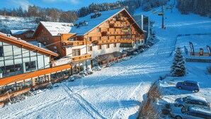 A ski resort with wooden cabins, a glass building, and a ski lift. - Hotel Meta Resort & Vine SPA (Szczyrk)