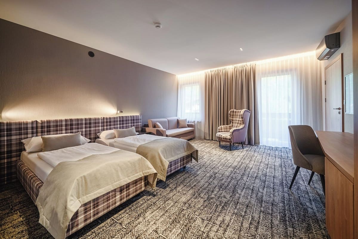 Habitación de hotel con dos camas, un sofá, una silla y un escritorio.
