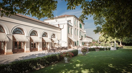 A building with arched windows and outdoor seating, surrounded by a well-maintained garden.