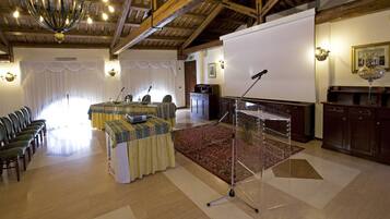 Une salle de conférence dotée d’un écran de projection blanc, d’une table avec un microphone et d’un sol recouvert de moquette.