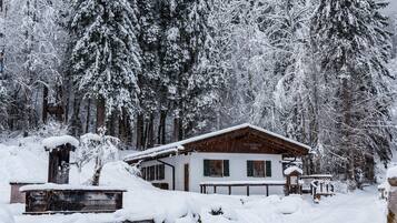 Une cabane en bois avec un toit en pente, entourée d’arbres couverts de neige.