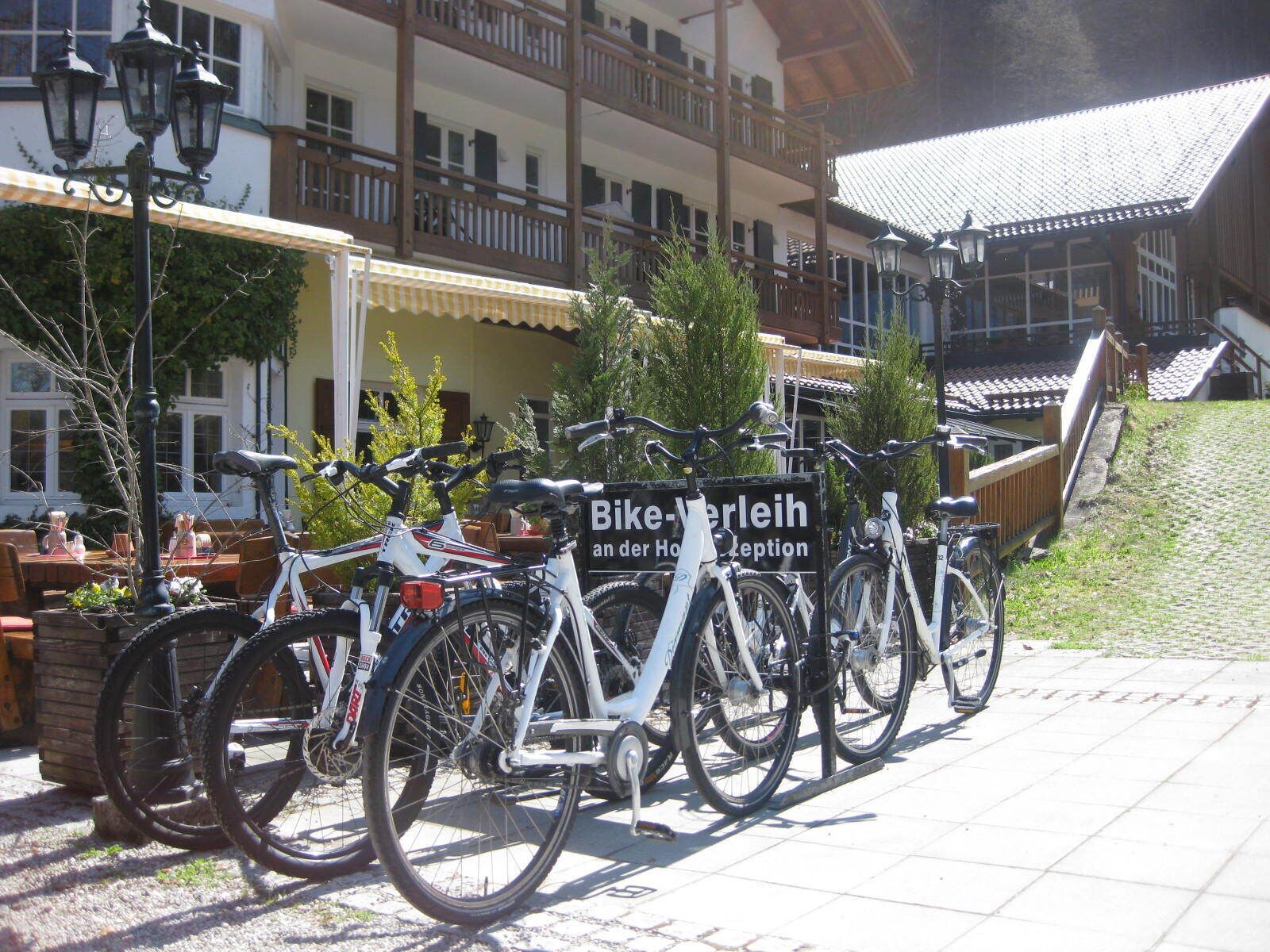Una fila de bicicletas estacionadas frente a un edificio con un letrero que dice "Bike-Verleih an der Hohen Rezeption".