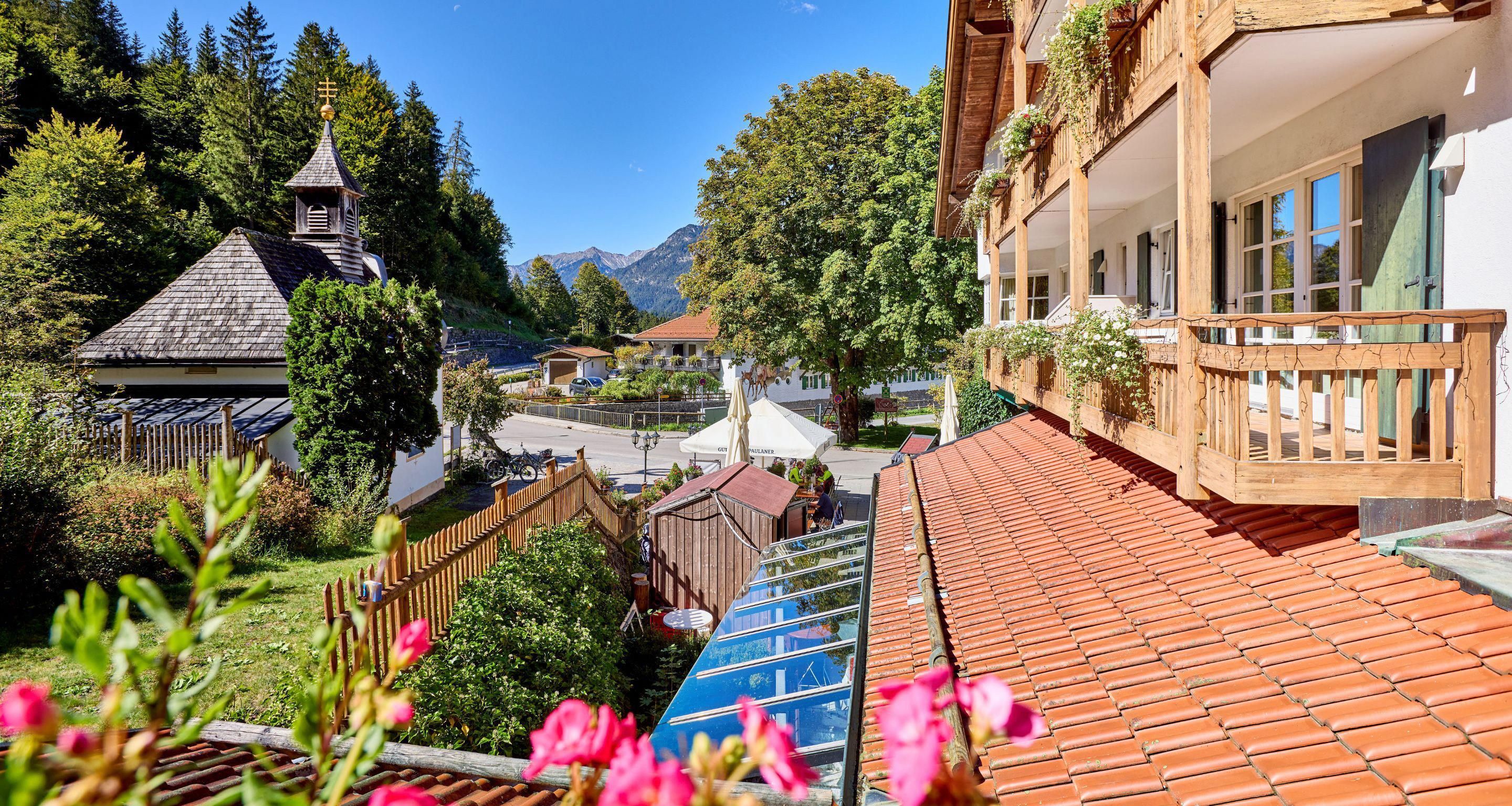 Una cabaña tradicional con techo inclinado, balcones de madera y vistas a una cordillera.