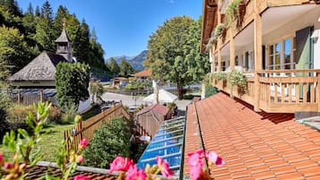 Una cabaña tradicional con techo inclinado, balcones de madera y vistas a una cordillera.