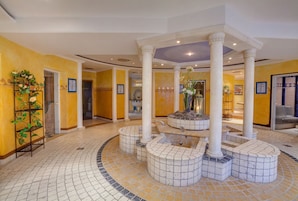 A hotel lobby with a circular seating area, columns, and a tiled floor.