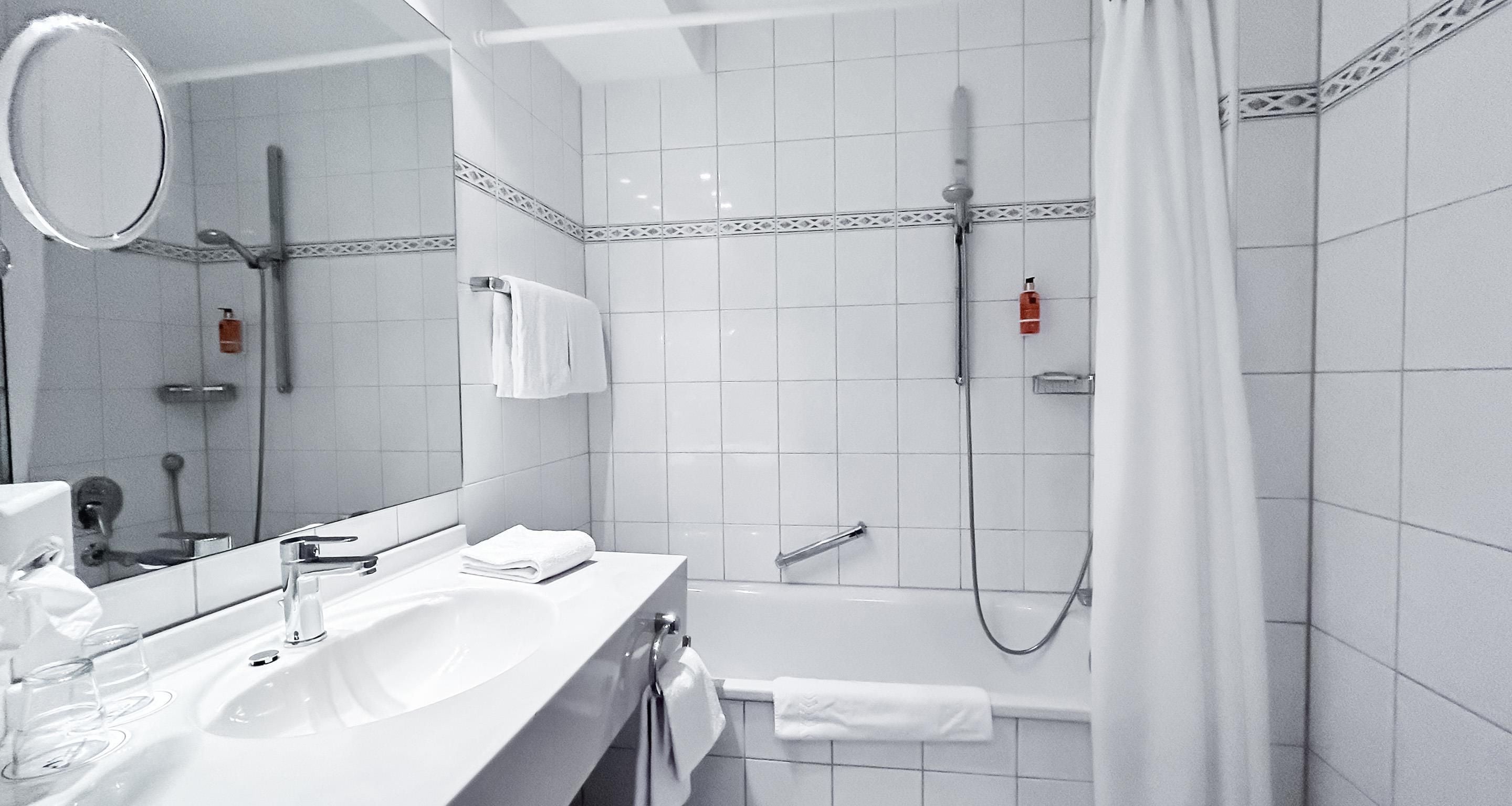 A modern bathroom with a sink, mirror, and shower area.