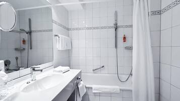 A modern bathroom with a sink, mirror, and shower area.