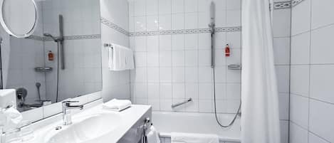 A modern bathroom with a sink, mirror, and shower area.