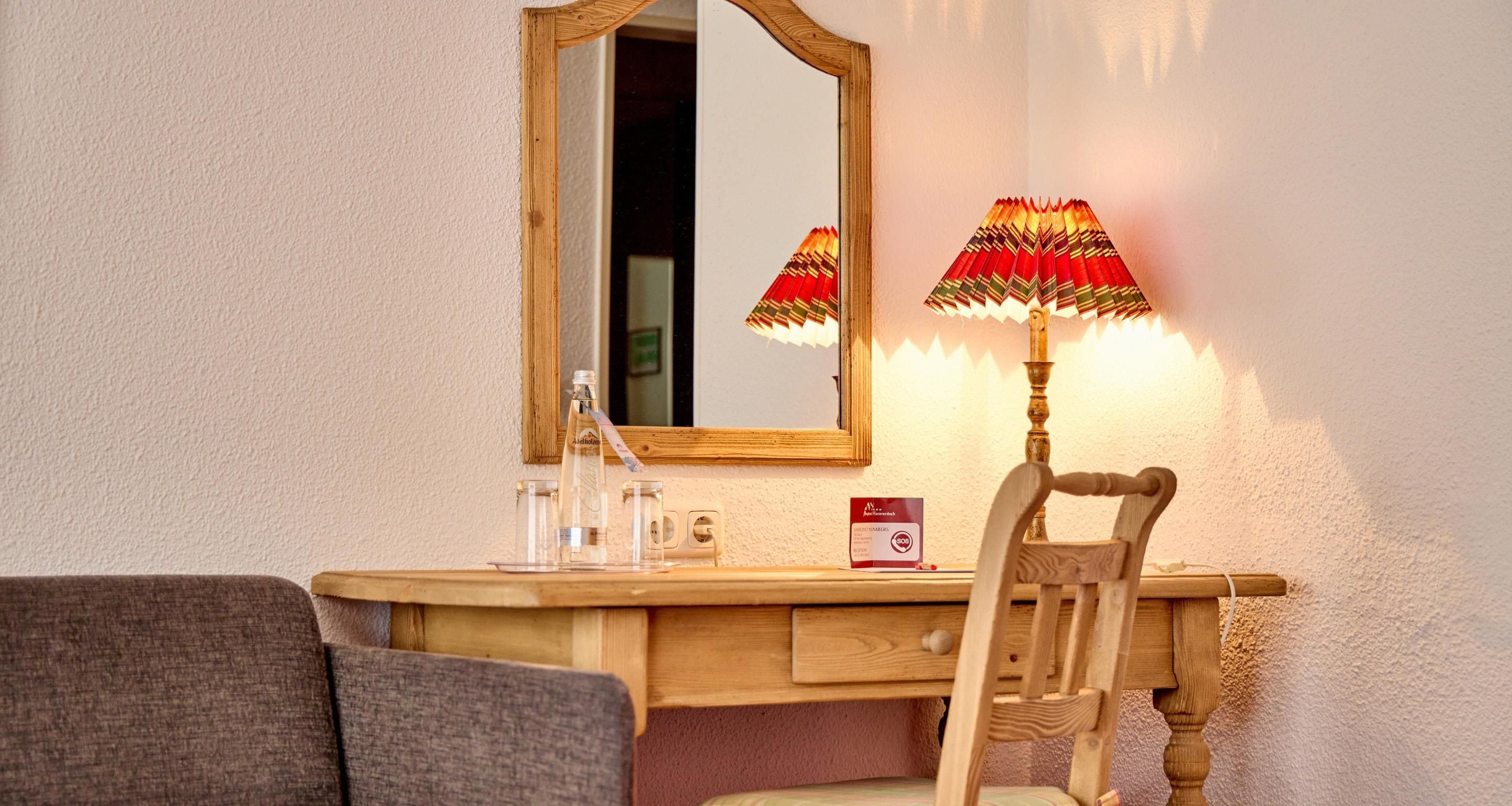 Un bureau en bois, avec un miroir, une lampe et une chaise.