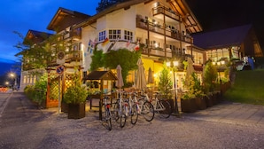 Un hotel de varios pisos con terraza al aire libre y bicicletas estacionadas adelante.