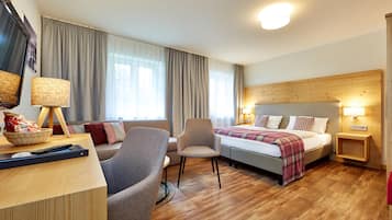 Une chambre d’hôtel avec un lit, un bureau doté d’une lampe, une chaise et un téléviseur.