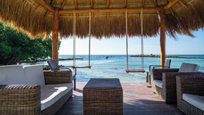 A covered outdoor seating area with wicker furniture, a swing, and a view of the ocean. - Hacienda Tres Rios Resort, Spa & Nature Park-All Inclusive (Playa del Carmen)
