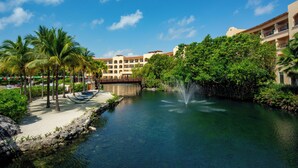 A resort with a water feature, palm trees, and a building with multiple balconies. - Kimpton Tres Rios All Inclusive by IHG (Playa del Carmen)