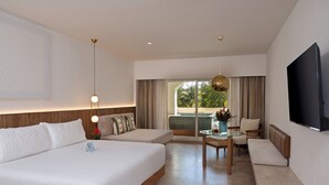 A modern hotel room with a large bed, a seating area with a table, and a TV mounted on the wall. - Kimpton Tres Rios All Inclusive by IHG (Playa del Carmen)